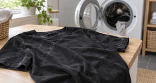 Maglia nera con residui chiari di lavaggio appoggiata accanto a una lavatrice con oblò aperto