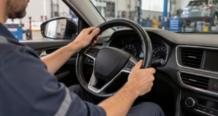 Conducente con le mani sul volante di un’auto ferma in officina durante un controllo dello sterzo